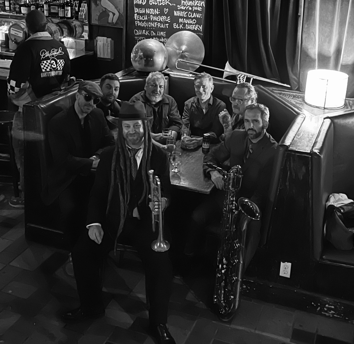 Black-and-white group portrait of Bobby J’s West Bank Social Club gathered around a table